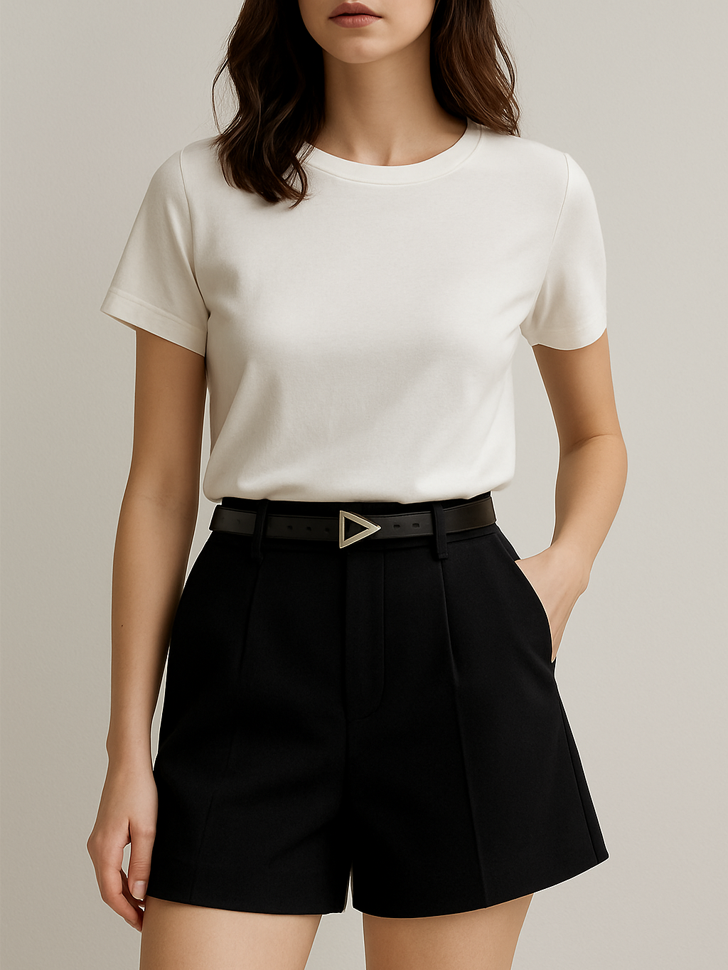 Person wearing a white t-shirt and black shorts with a belt on a neutral background