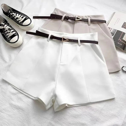 White shorts with black belts and black sneakers on a light background