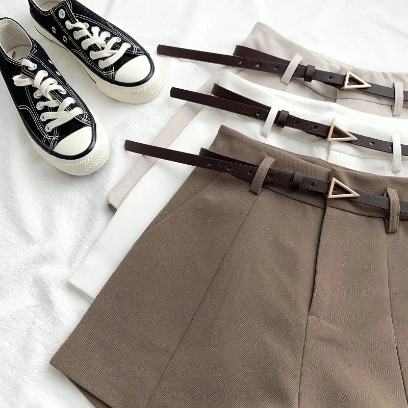 Brown pants with belts and black sneakers on a light background